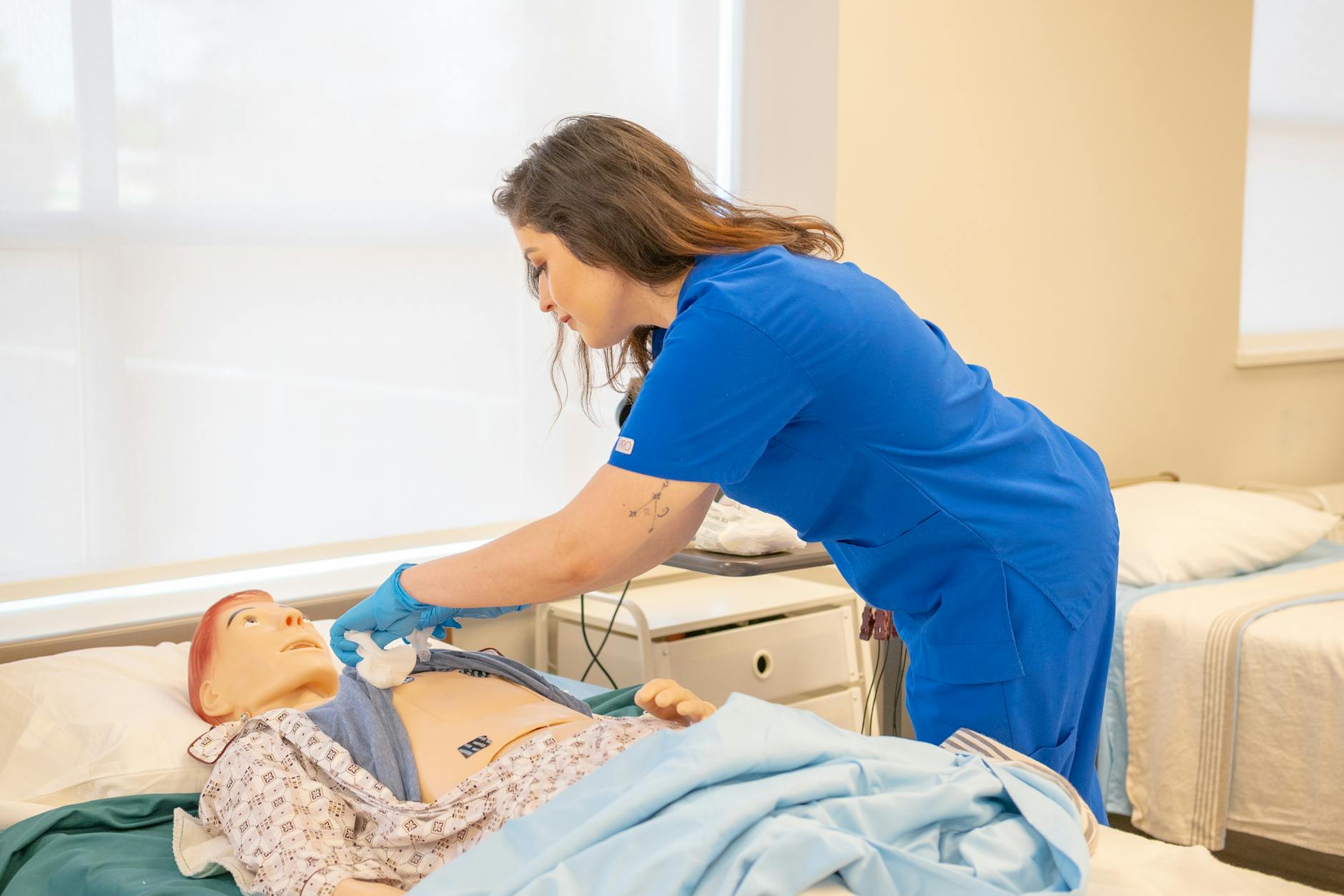 nurse practicing on training dummy in medical facility